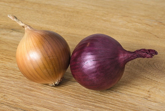 Cebule czerwonej i brązowej cebuli na drewnianej desce kuchennej