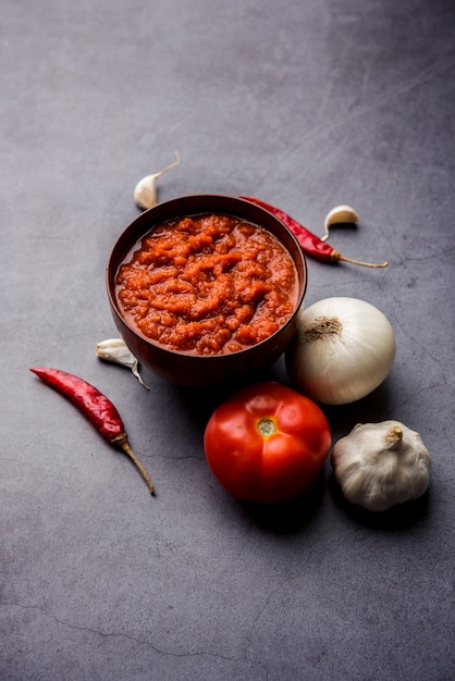 Cebulowy pomidor masala lub puree do indyjskiego sosu, podawane w misce z surowym tamatarem, pays i lehsun oraz czerwonym chilli,