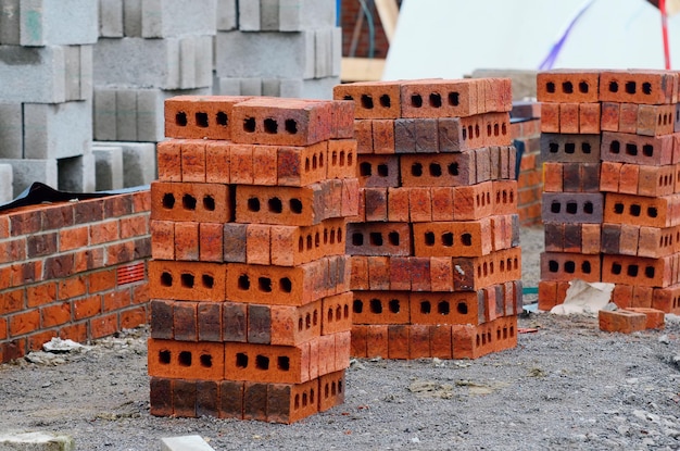 Cegła czerwona i bloczki betonowe dostarczone na plac budowy i umieszczone obok miejsca pracy