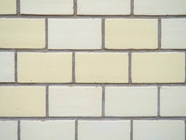 Cegły o różnych kolorach są równomiernie ułożone Ściana z żółtego i białego kamienia
