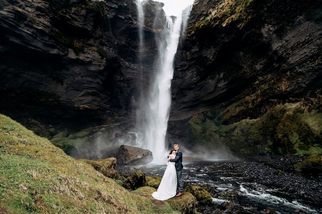 Cel podróży islandia ślub w pobliżu wodospadu kvernufoss para ślubna stoi w pobliżu wodospadu