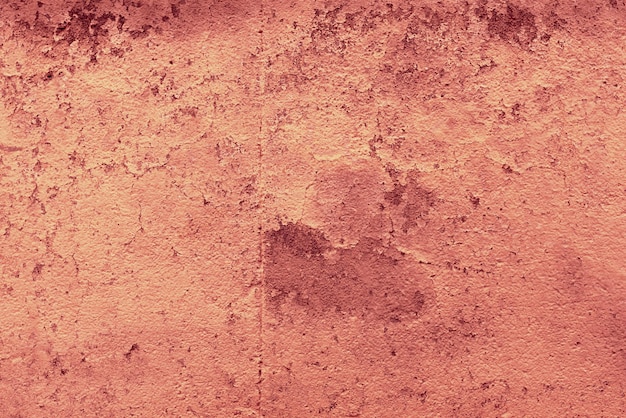 Cementowa ściana z łuszczącą się czerwonawą farbą