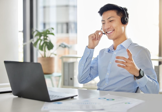 Centrum obsługi klienta i telemarketing z konsultantem azjatyckim pracującym na laptopie z zestawem słuchawkowym Skontaktuj się z nami crm i skonsultuj się z mężczyzną pracującym w swoim biurze sprzedaży z uśmiechem