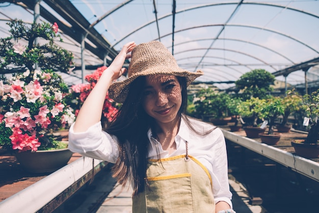 Centrum szklarni Bonsai. rzędy małych drzewek, kobieta pracująca i dbająca o rośliny