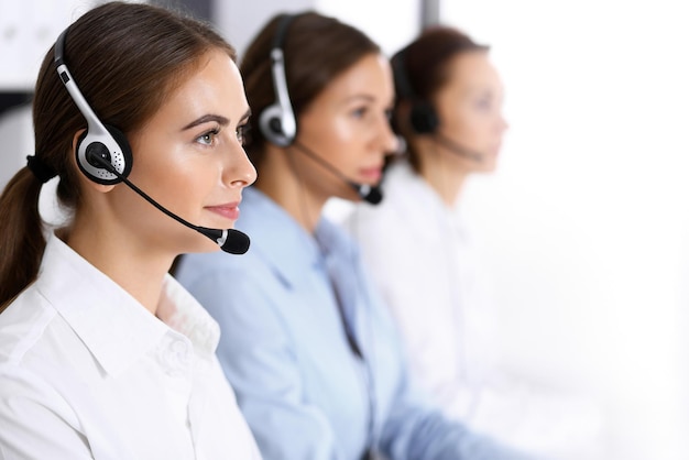 Centrum telefoniczne. Grupa operatorów w pracy. Skoncentruj się na pięknej kobiecie biznesu w zestawie słuchawkowym.