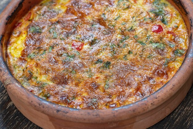 Ceramiczna miska z warzywną frittatą proste wegetariańskie jedzenie Frittata z pomidorową papryką, cebulą i serem na drewnianym stole z bliska Włoski omlet jajeczny