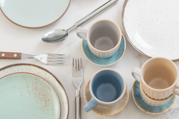 Ceramiczne kubki i talerze na białym marmurowym stole