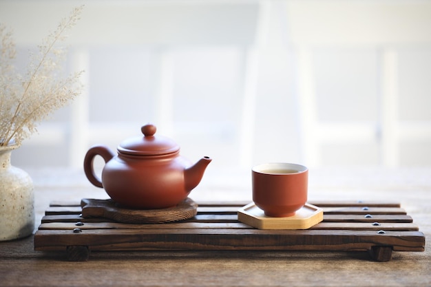Ceramiczny dzbanek do herbaty i filiżanka herbaty na drewnianej tacy