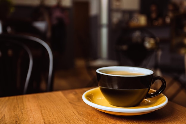 Ceramiczny kubek czarnej kawy na drewnianym stole w kawiarni