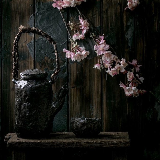 Ceramiczny kubek do picia herbaty i czajniczek z kwitnącymi gałęziami wiśni