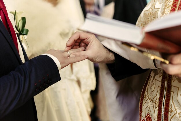 Zdjęcie ceremonia ślubna stylowej eleganckiej blond panny młodej i szczęśliwego pana młodego zakładającego obrączki w starym kościele