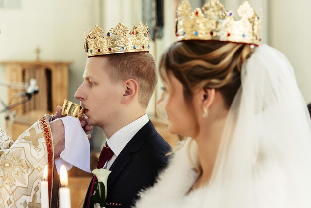 Zdjęcie ceremonia ślubna szczęśliwej eleganckiej blondynki panny młodej i stylowego pana młodego trzymającego świece w starym kościele