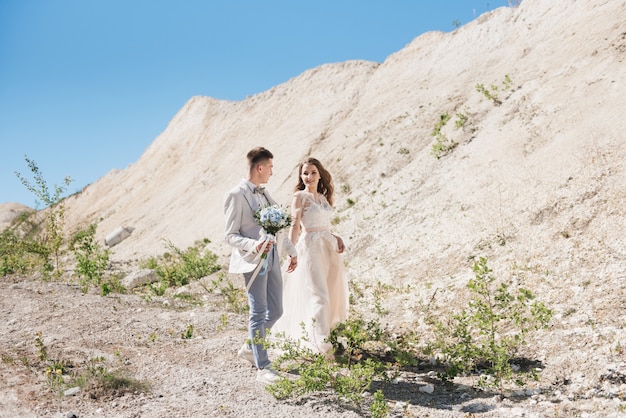 Ceremonia ślubna w górach. Narzeczeni stojący przed piaszczystymi górami. Szczęśliwa para, piękny ślub w malowniczej okolicy