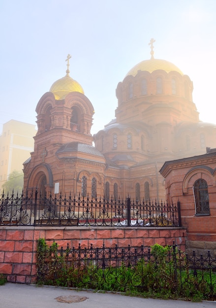 Cerkiew ze złotą kopułą w rosyjsko-bizantyjskim stylu architektonicznym w porannej mgle. Syberia, Rosja