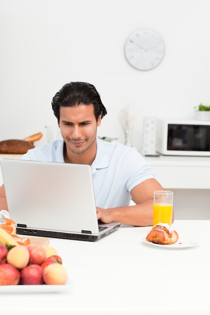 Charyzmatyczny latynoski mężczyzna pracuje na jego laptopie w kuchni