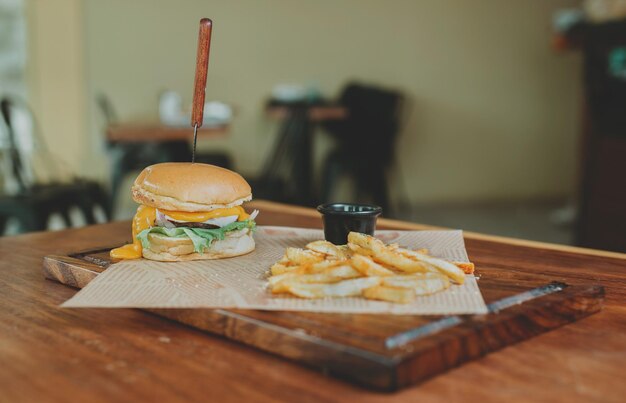 Zdjęcie cheeseburger z frytkami serwowany na drewnianym stole z przestrzenią do kopiowania pyszny hamburger z frytekami na drewninowym stole