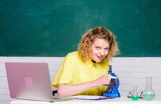 Zdjęcie chemia klasa dziewczyna w klasie laboratorium z laptopem biologia eksperyment badania robi notatki o wynikach badań chemii naukowiec w szkolnym laboratorium szczęśliwy uczeń z mikroskopem i zlewką