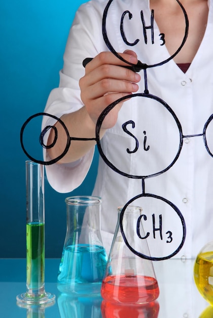 Chemik kobieta pisze formuły na szkle na niebieskim tle