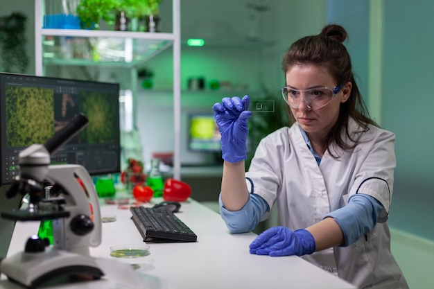 Zdjęcie chemik naukowiec patrzący na próbkę zielonego liścia sprawdzającą mutację genetyczną do eksperymentu biologicznego