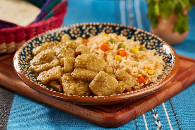 Zdjęcie chicharron en salsa verde con arroz rojo servido en plato de barro mexicano