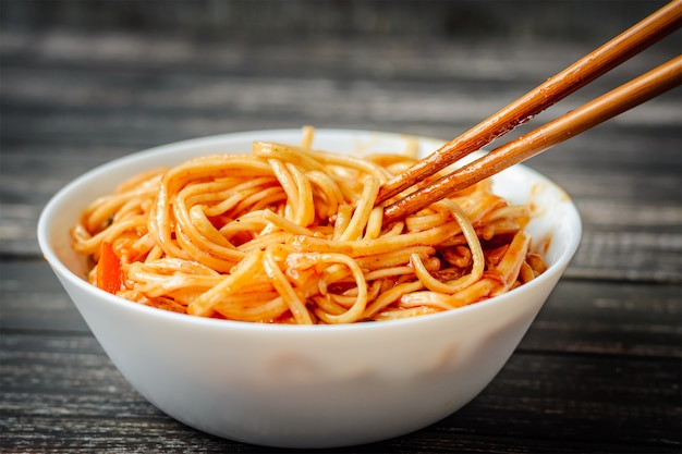 Chineese wok udon z kurczakiem na ciemnym tle