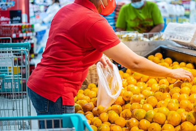 Chinki noszą maskę i kupują pomarańcze, aby oddać szacunek przodkom podczas festiwalu Chińskiego Nowego Roku na dziale owoców w domu towarowym selektywna ostrość zamazane tło Zbliżenie