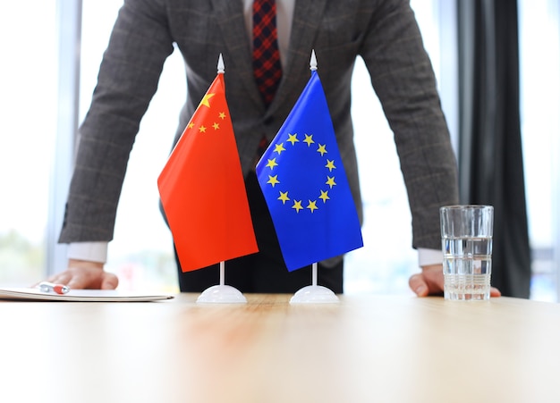 Chińska flaga i flaga Unii Europejskiej z biznesmenem w pobliżu