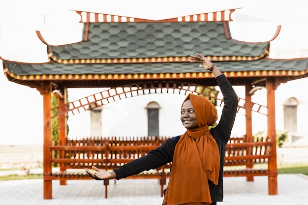 Chińska Medytacja Qigong I Trening Sportowy Na świeżym Powietrzu. Czarna Muzułmanka Medytuje Na świeżym Powietrzu W Pobliżu Chińskiej Altany.