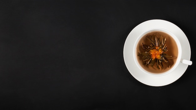 Chiński herbaciany kwiat z białym kubkiem na ciemnym tle
