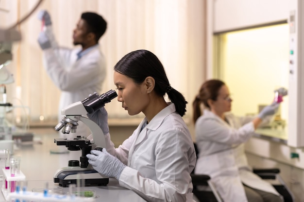 Chiński naukowiec patrząc w mikroskop w laboratorium