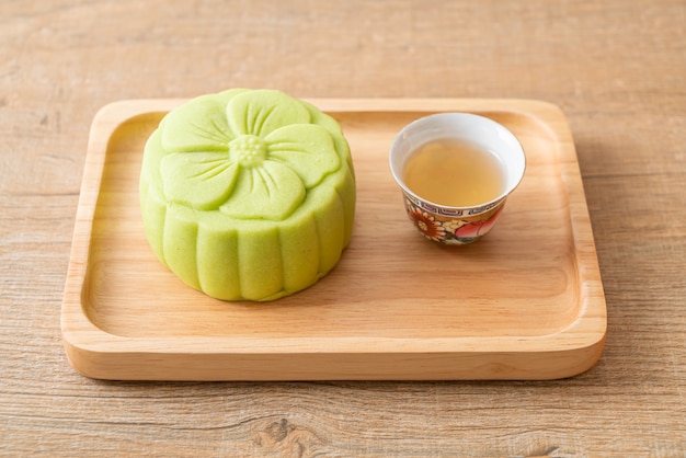 Chiński tort księżycowy o smaku zielonej herbaty z herbatą na drewnianym talerzu