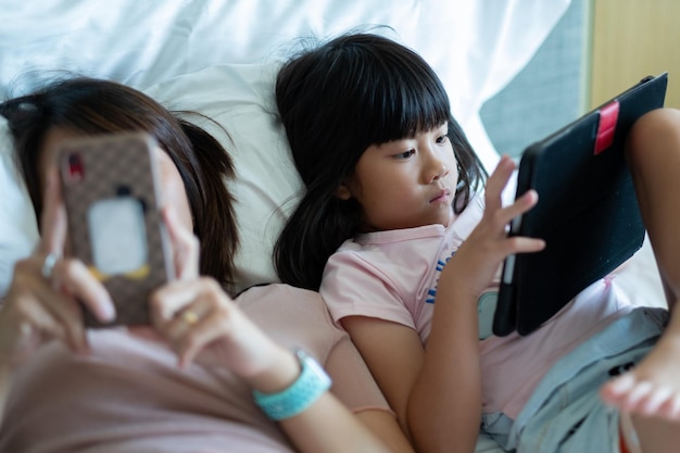 Chińskie dziecko bawiące się smartfonem z tabletem uzależnionym od matki dziecka