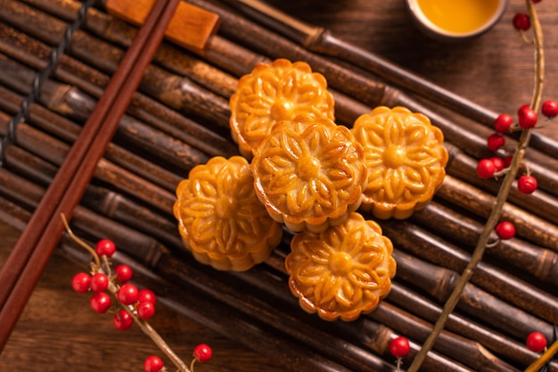 Chińskie tradycyjne ciasto Moon cake Mooncake z filiżankami herbaty na bambusowej tacy do serwowania na drewnianym tle na Święto Środka Jesieni, widok z góry, płasko leżał