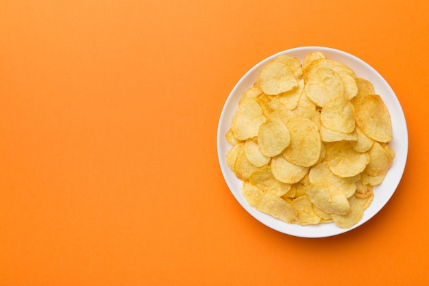 Chipsy ziemniaczane w misce na białym tle Pyszne chrupiące chipsy ziemniaczane w misce Miejsce na tekst Widok z góry