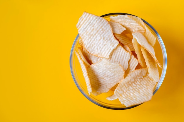 Chipsy ziemniaczane w szklanych miskach na żółtym tle Śmieciowe niezdrowe chipsy jedzenie imprezowe fast food