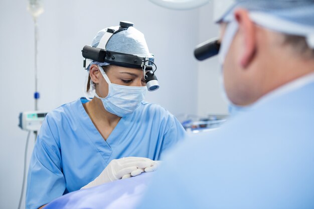 Chirurdzy noszący chirurgiczne lupy podczas obsługi pacjenta