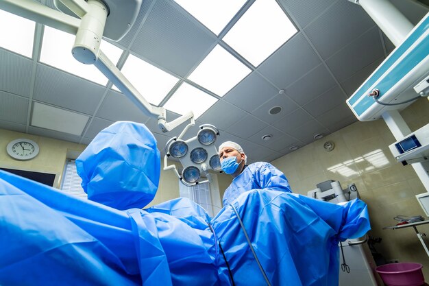 Chirurdzy pracujący na sali operacyjnej. Szpital tło. Dwóch lekarzy płci męskiej w pracy. Okrągłe tło operacji na rdzeniu kręgowym, kręgu.