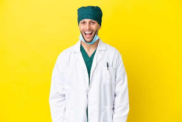 Zdjęcie chirurg blondyn w zielonym mundurze na żółtym tle z niespodzianką wyrazem twarzy