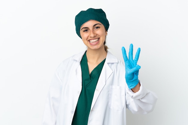 Chirurg kaukaski kobieta na białym tle szczęśliwy i licząc trzy palcami