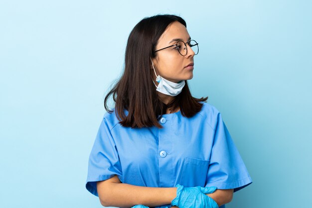 Chirurg kobieta nad odosobnioną błękit ścianą utrzymuje ręki krzyżować
