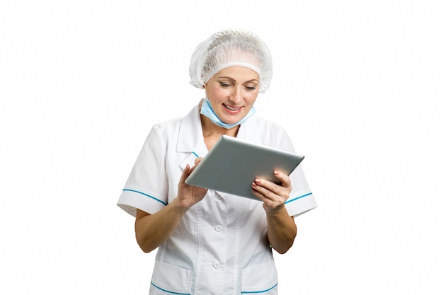 Chirurg kobieta za pomocą cyfrowego tabletu. Piękna dojrzała kobieta chirurg patrząc na tablecie komputera i uśmiechnięta, biała.