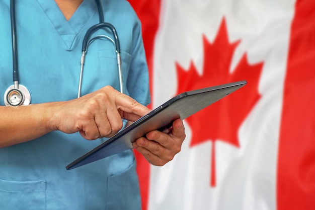 Chirurg lub lekarz za pomocą cyfrowego tabletu na tle flagi Kanady
