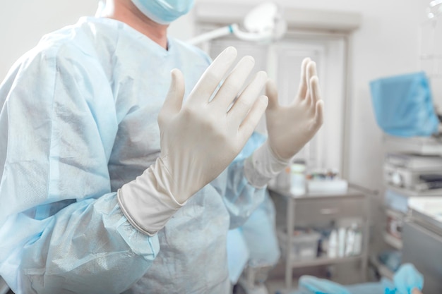 Chirurg trzyma ręce zdezynfekowane w białych rękawiczkach przed operacją