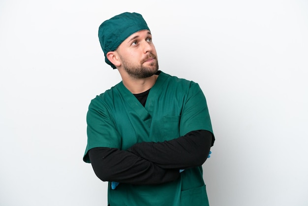 Chirurg w zielonym mundurze na białym tle wykonujący gest wątpliwości podczas podnoszenia ramion