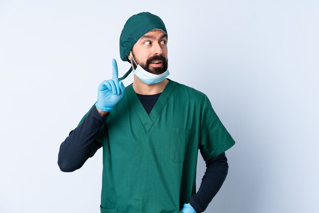 Chirurga mężczyzna w zieleń mundurze nad odosobnioną ścianą myśleć pomysł wskazuje palec up