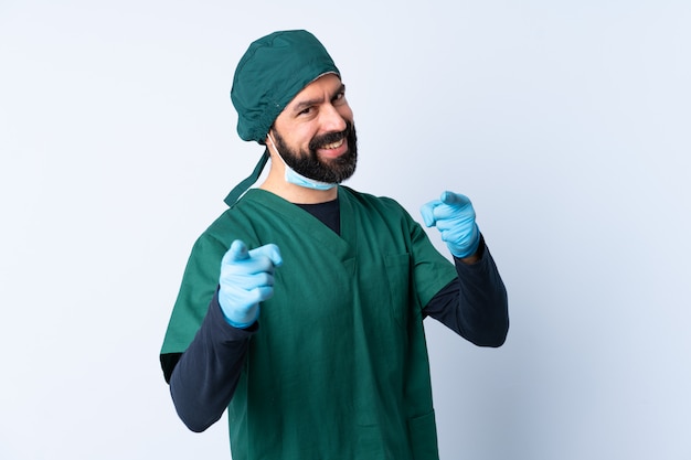Chirurga mężczyzna w zieleń mundurze nad odosobnioną ścianą wskazuje przód z szczęśliwym wyrażeniem