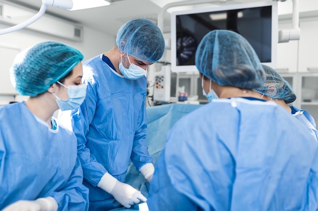 Chirurgia w trybie pilnym Profesjonalni inteligentni chirurdzy stojący w pobliżu pacjenta i przeprowadzający operację ratując mu życie