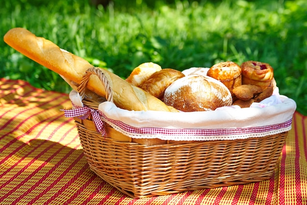 Chleb, bagietka i rogaliki w koszyku piknikowym