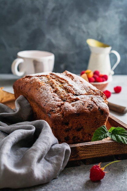 Chleb bananowy z malinami, zawinięty na szarej betonowej powierzchni vintage