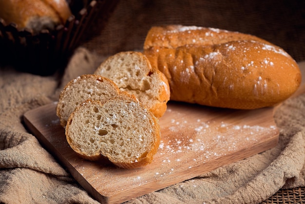 Chleb francuski posypany cukrem pudrem na drewnianej desce do krojenia